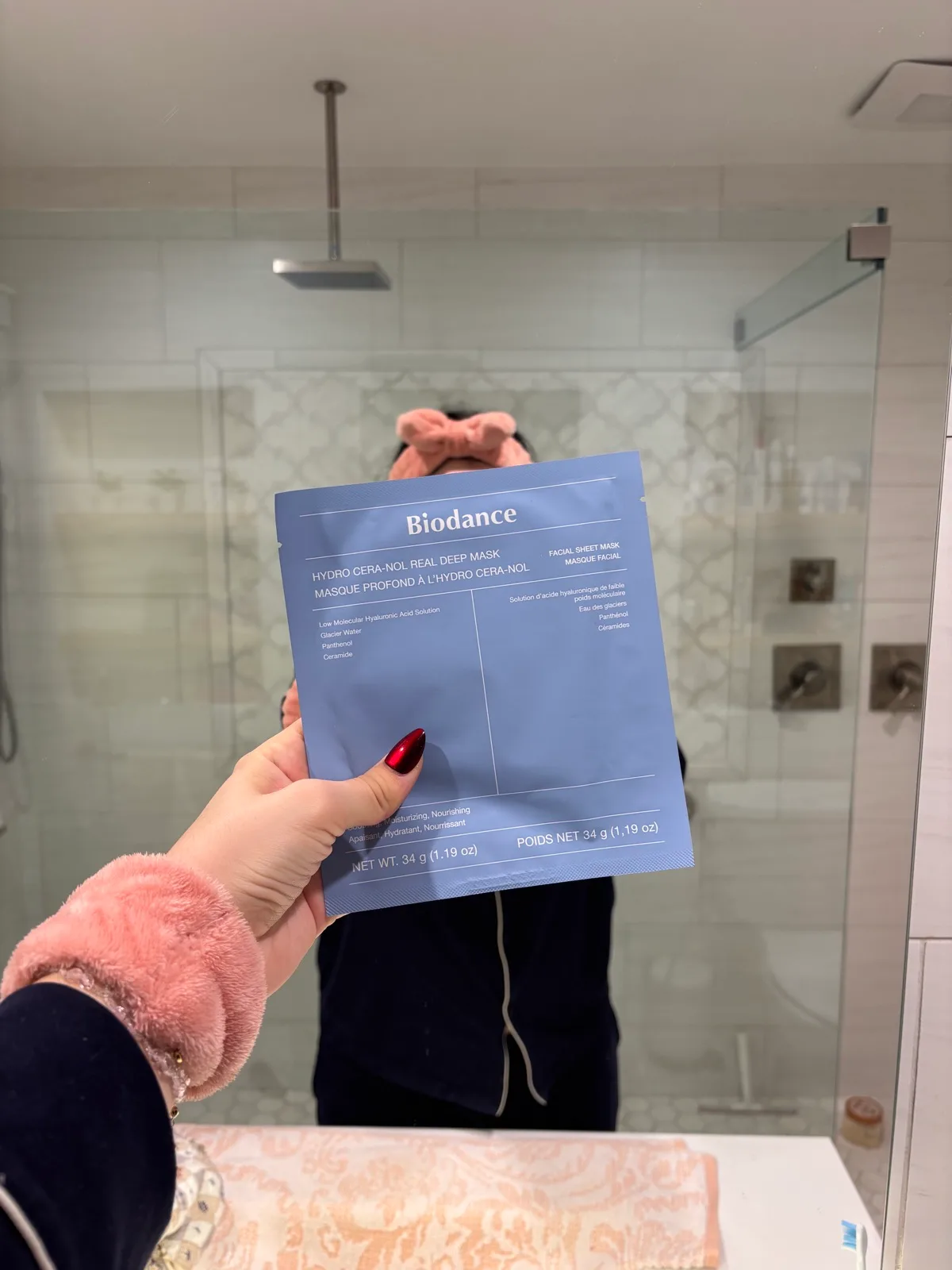 Biodance face mask held up in a mirror while wearing pajamas
