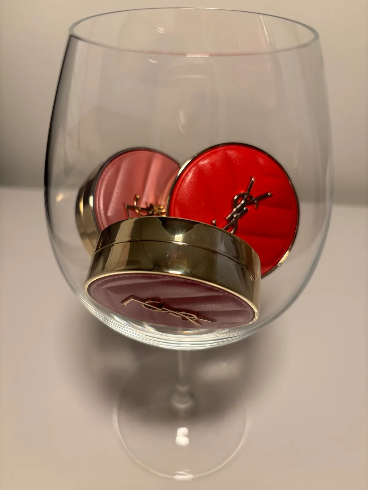 Three YSL blush compacts creatively arranged inside a wine glass
